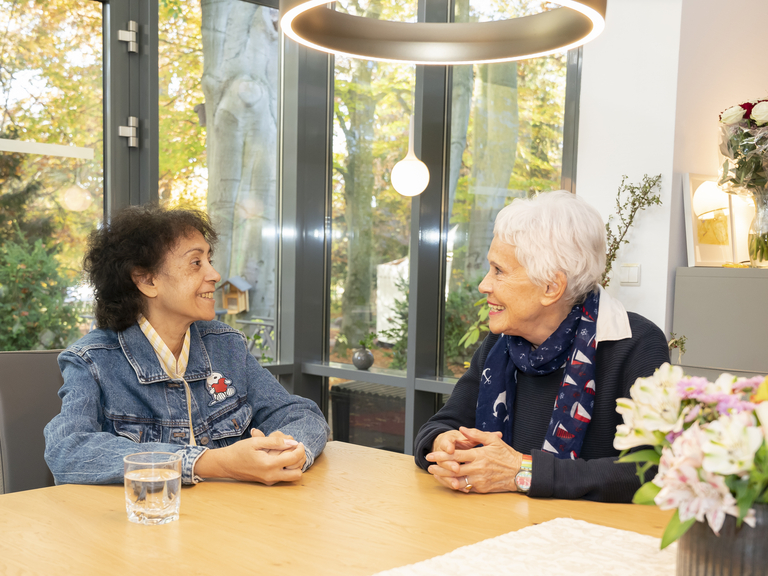 Zwei ältere Damen sitzend erzählend am Tisch - Verschiedene Therapieangebote für Hospizgäste - Diakonie Hospiz Wannsee