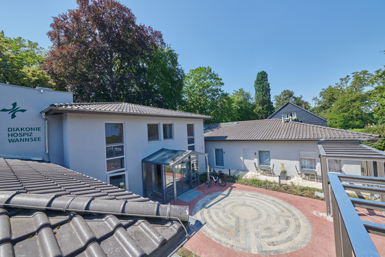 Blick auf den Eingangsbereich mit Pflanzengerüst und Pflasterung vom Dachgeschoss des Stationären Diakonie Hospiz Wannsee in Berlin. Blick auf den Eingangsbereich mit Pflanzengerüst und Pflasterung vom Dachgeschoss des Stationären Diakonie Hospiz Wannsee in Berlin.